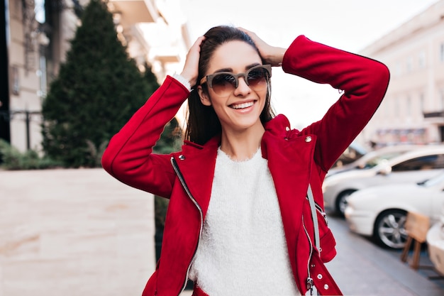 Foto gratuita entusiasta mujer morena con gafas de sol riendo en un día soleado en la calle