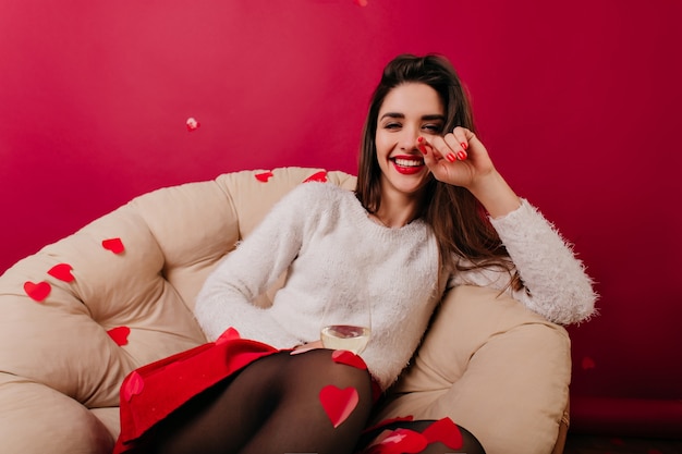 Entusiasta mujer morena con uñas rojas sonriendo a la cámara