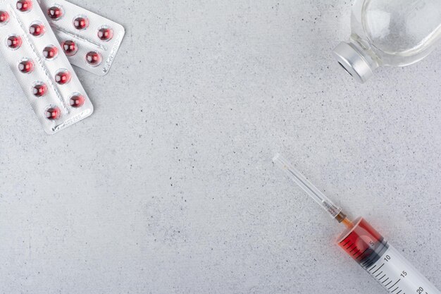 Envases de pastillas, ampollas y jeringas sobre superficie de mármol. Foto de alta calidad