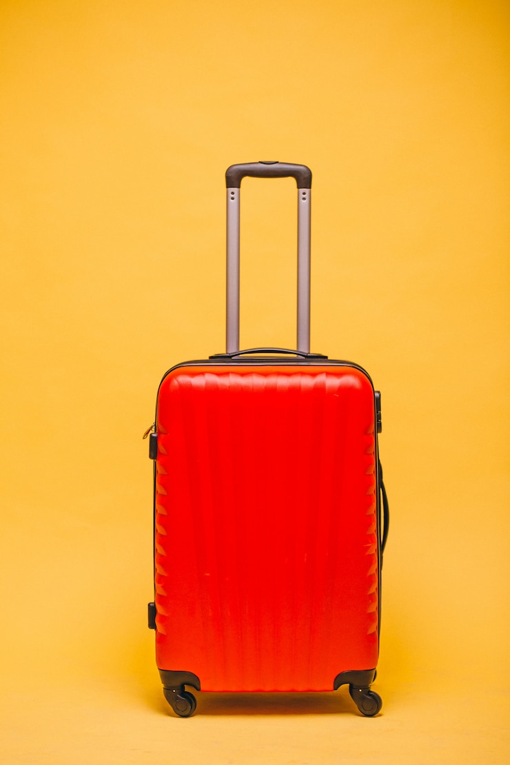 Foto gratuito equipaje rojo sobre un fondo amarillo aislado