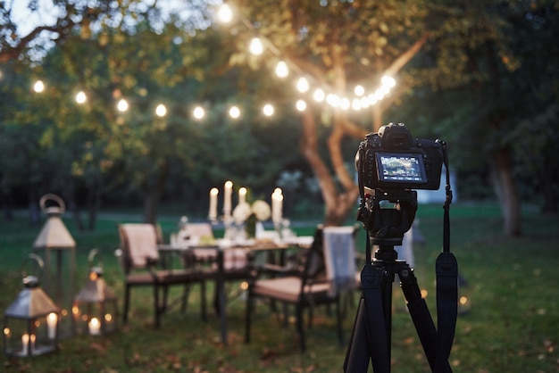 Foto gratuita equipamiento profesional. cámara en el trípode en el campo frente a la mesa preparada al atardecer