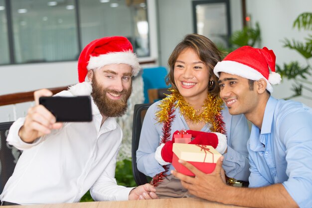Equipo alegre del negocio que toma el selfie de la Navidad