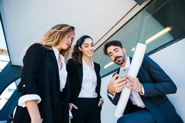 Equipo de arquitectos con plano y smartphone