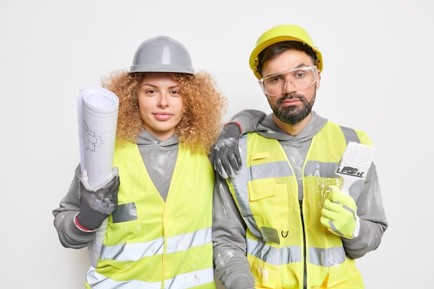 Equipo de arquitectos profesionales vestidos con uniforme trabajan juntos sostienen planos y trabajos de pincel para el proyecto de construcción de edificios en el sitio