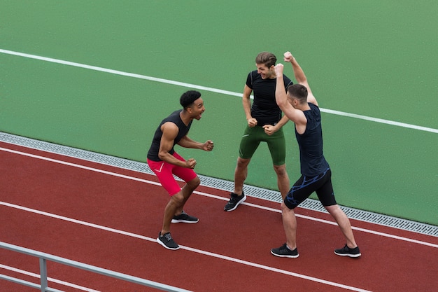 Equipo de atleta multiétnico feliz hacer gesto ganador