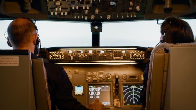 Equipo de aviadores que usan los botones del tablero para despegar con el avión, arrancar el motor y navegar por el panel de control. Vuelo de aviación con brújula de radar e interruptor de palanca de parabrisas.