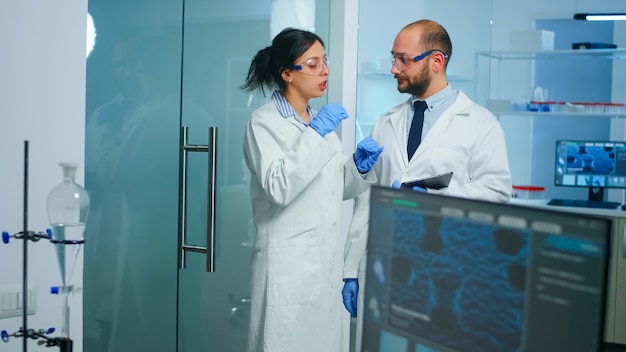 Foto gratuita equipo de científicos médicos que llevan a cabo el desarrollo de vacunas con la ayuda de alta tecnología, un médico con tableta analizando nueva información