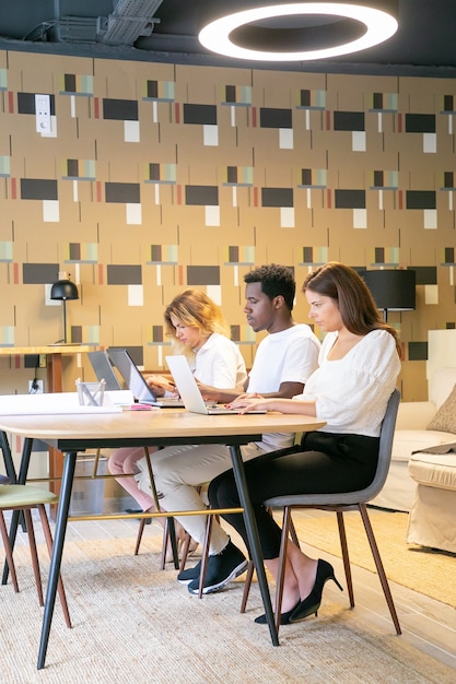 Equipo creativo sentados juntos a la mesa con planos y trabajando en el proyecto