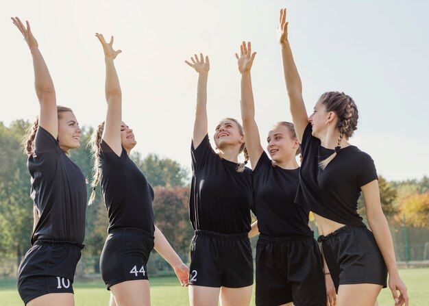 Equipo deportivo femenino levantando las manos