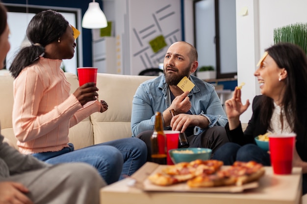 Equipo diverso de compañeros de trabajo jugando charadas después del trabajo