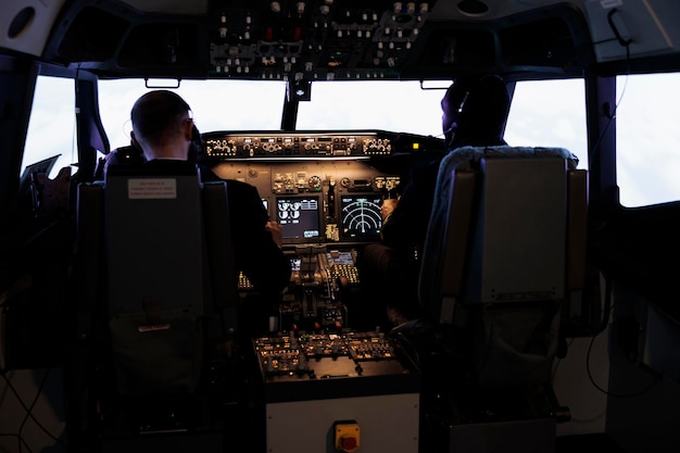 Equipo diverso de miembros de la tripulación aérea que utilizan el comando de control para volar el avión en la cabina del avión, presionando los botones de encendido en el tablero. Capitán y piloto haciendo trabajo en equipo volando en avión con palanca de motor.