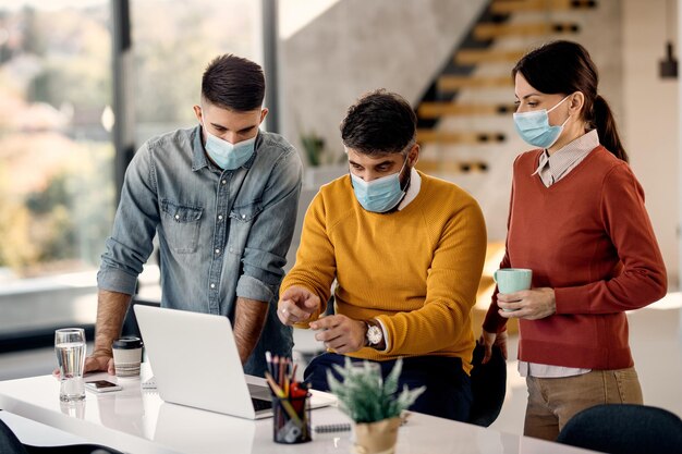 Equipo de empresarios que cooperan mientras analizan planes en una computadora en la oficina