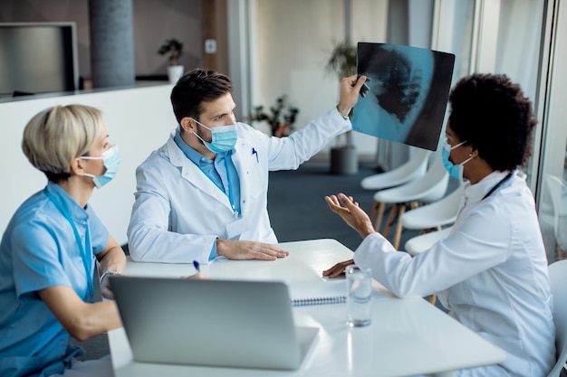 Equipo de expertos en atención médica que examinan la imagen de rayos X en la clínica médica