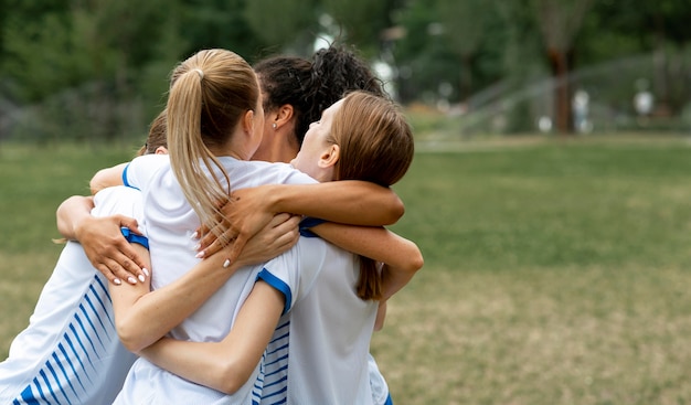 Foto gratuita equipo feliz abrazándose en el campo