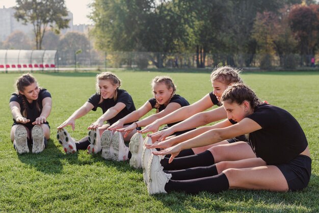 Equipo femenino haciendo ejercicios de calentamiento