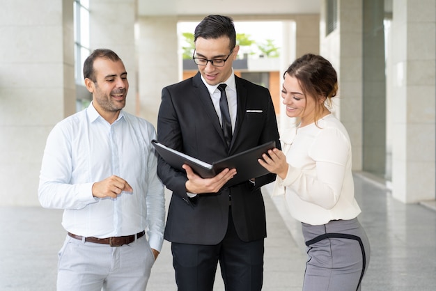 Equipo de financieros felices leyendo el informe sobre el progreso de la empresa