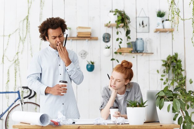 Equipo internacional multirracial de dos trabajadores creativos que enfrentan problemas