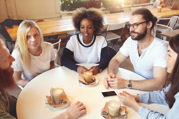 Foto gratuita equipo de jóvenes colegas que se reúnen en el café