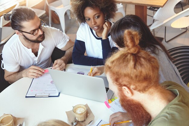 Equipo de jóvenes colegas que se reúnen en el café