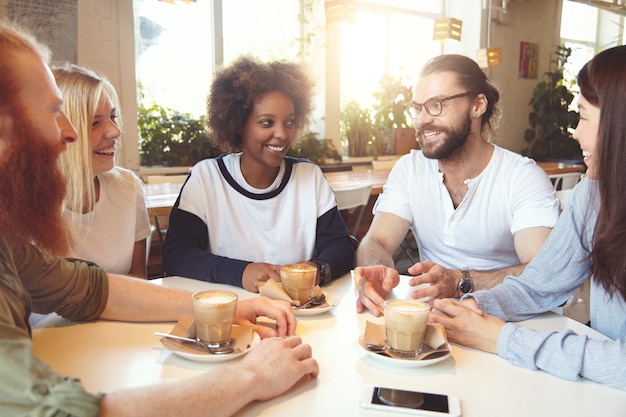 Equipo de jóvenes colegas que se reúnen en el café