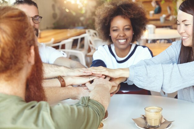 Equipo de jóvenes colegas que se reúnen en el café