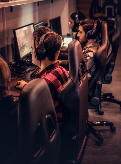 Un equipo de jugadores adolescentes juega en un videojuego multijugador en PC en un club de juegos.