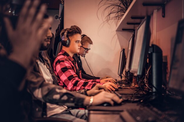 Un equipo de jugadores adolescentes juega en un videojuego multijugador en PC en un club de juegos.