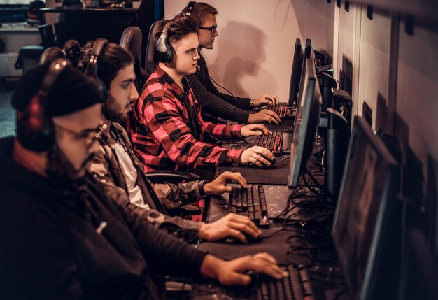 Un equipo de jugadores adolescentes juega en un videojuego multijugador en PC en un club de juegos.