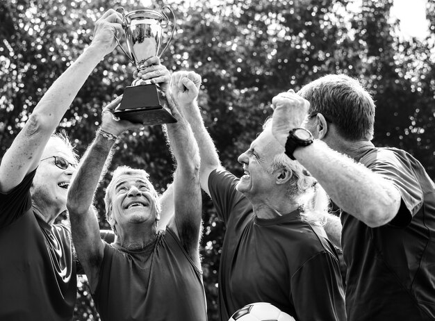 Equipo de jugadores de fútbol maduros ganando la copa