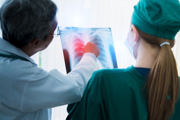 El equipo médico asiático examina la película de rayos X del análisis del paciente para encontrar la mejor solución para la operación y tratar el concepto de ideas de salud