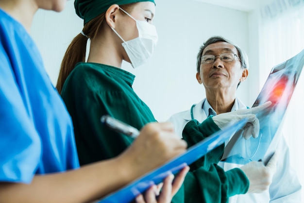 El equipo médico asiático examina la película de rayos X del análisis del paciente para encontrar la mejor solución para la operación y tratar el concepto de ideas de salud