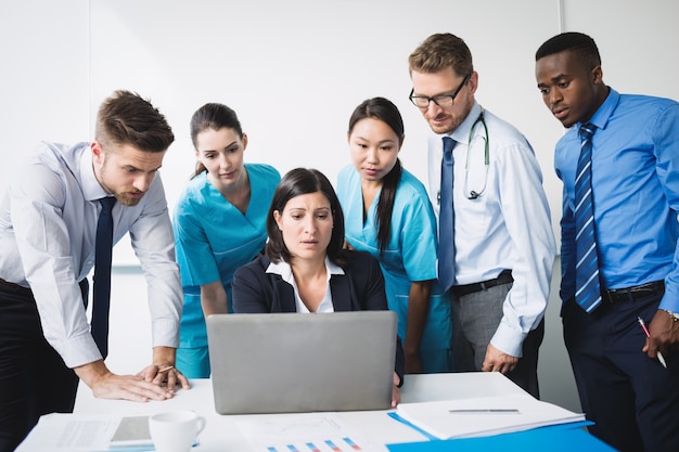 Equipo de médico discutiendo sobre portátil en reunión