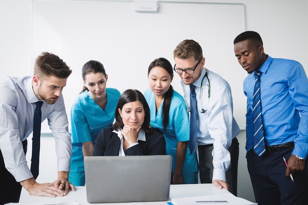 Equipo de médico discutiendo sobre portátil en reunión