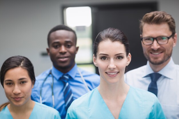 Equipo médico sonriente de pie juntos en el pasillo del hospital
