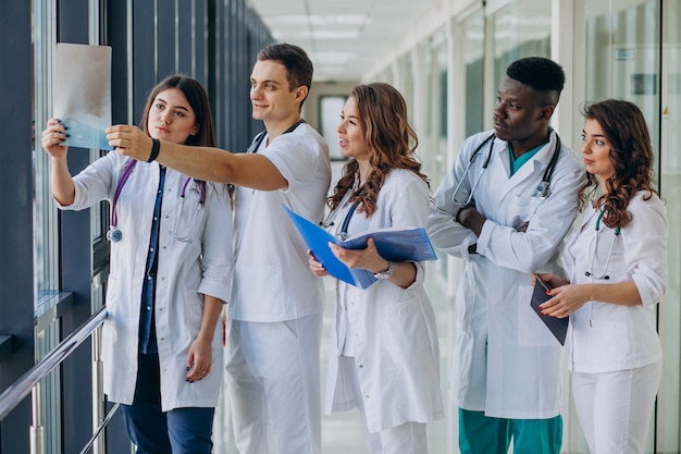 Equipo de médicos especialistas jóvenes de pie en el pasillo del hospital.