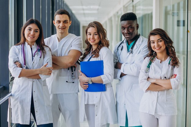 Equipo de médicos especialistas jóvenes de pie en el pasillo del hospital.