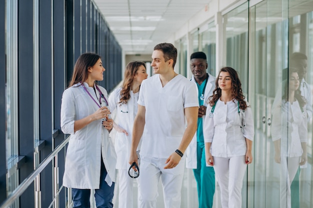 Equipo de médicos especialistas jóvenes de pie en el pasillo del hospital.
