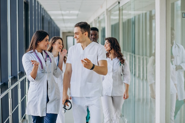 Equipo de médicos especialistas jóvenes de pie en el pasillo del hospital.