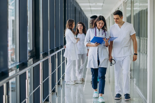 Equipo de médicos especialistas jóvenes de pie en el pasillo del hospital.