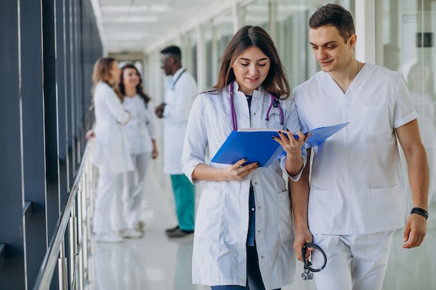 Equipo de médicos especialistas jóvenes de pie en el pasillo del hospital.