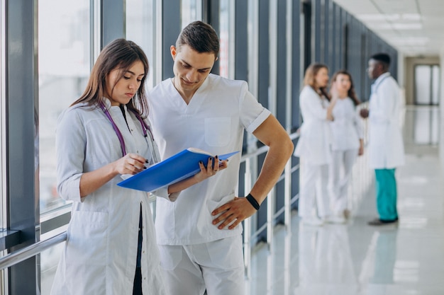 Equipo de médicos especialistas jóvenes de pie en el pasillo del hospital.