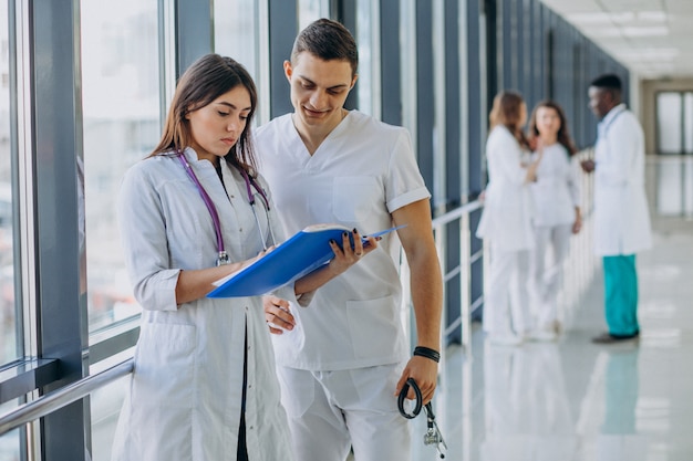 Foto gratuita equipo de médicos especialistas jóvenes de pie en el pasillo del hospital.