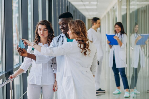 Equipo de médicos especialistas jóvenes de pie en el pasillo del hospital.