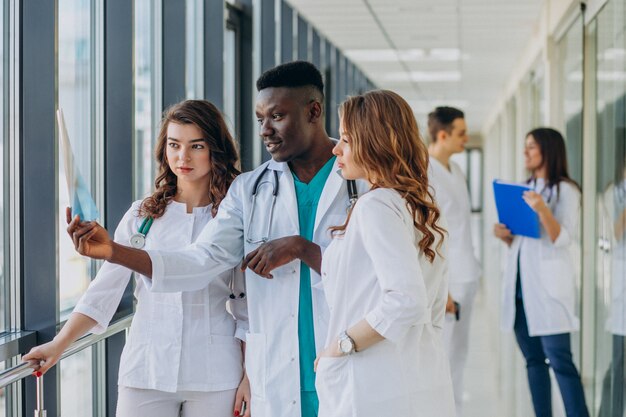 Equipo de médicos especialistas jóvenes de pie en el pasillo del hospital.