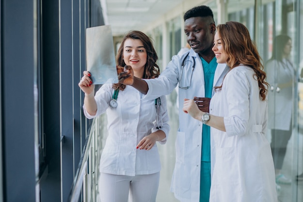 Equipo de médicos especialistas jóvenes de pie en el pasillo del hospital.