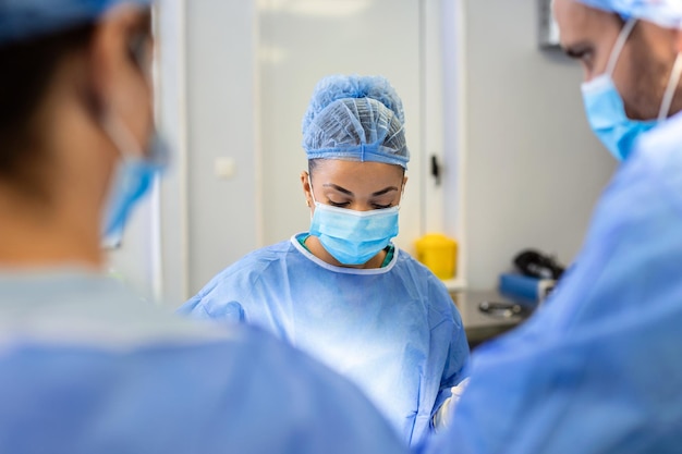 El equipo de médicos está de pie en la sala de emergencias Los cirujanos multiétnicos están trabajando en el quirófano del hospital Llevan batas azules