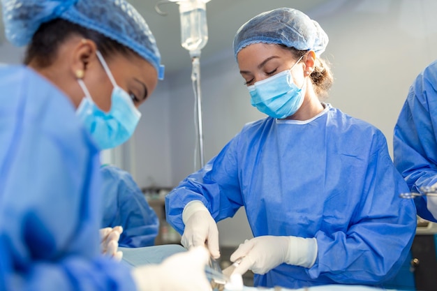 Equipo de médicos profesionales que realizan operaciones en el quirófano Equipo médico que realiza operaciones quirúrgicas en un quirófano moderno y luminoso