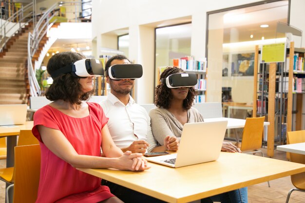 Equipo multirracial de estudiantes adultos con auriculares VR