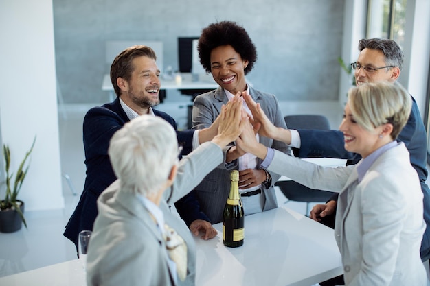 Equipo de negocios exitoso juntando manos en unidad mientras celebra en la oficina