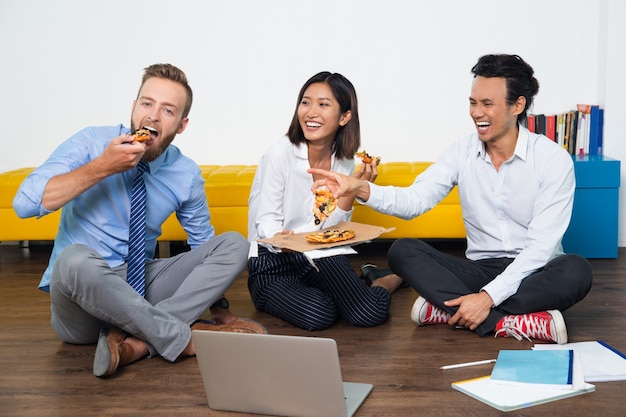 Equipo de negocios feliz riéndose de hombre con la pizza